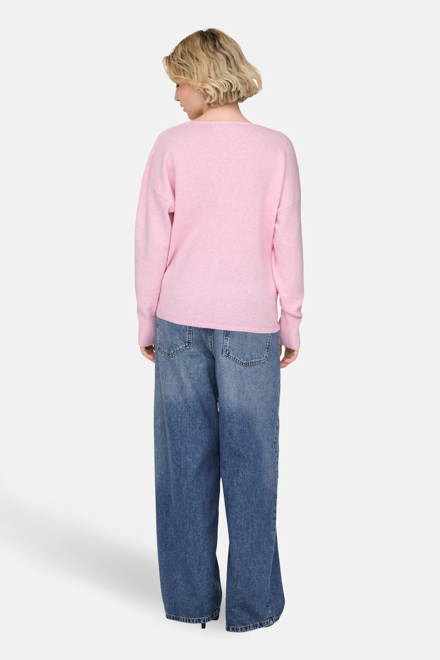 Roze V-hals trui van ONLY, gedragen met een wijde blauwe jeans.