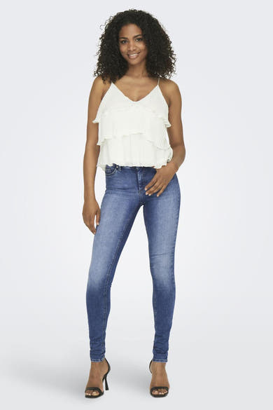 Jean skinny bleu moyen denim de ONLY, porté avec un haut et des talons hauts noirs.