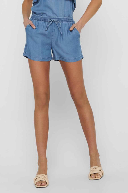 Short bleu en jean de ONLY, avec cordon de serrage et poches latérales, porté avec des sandales nude.
