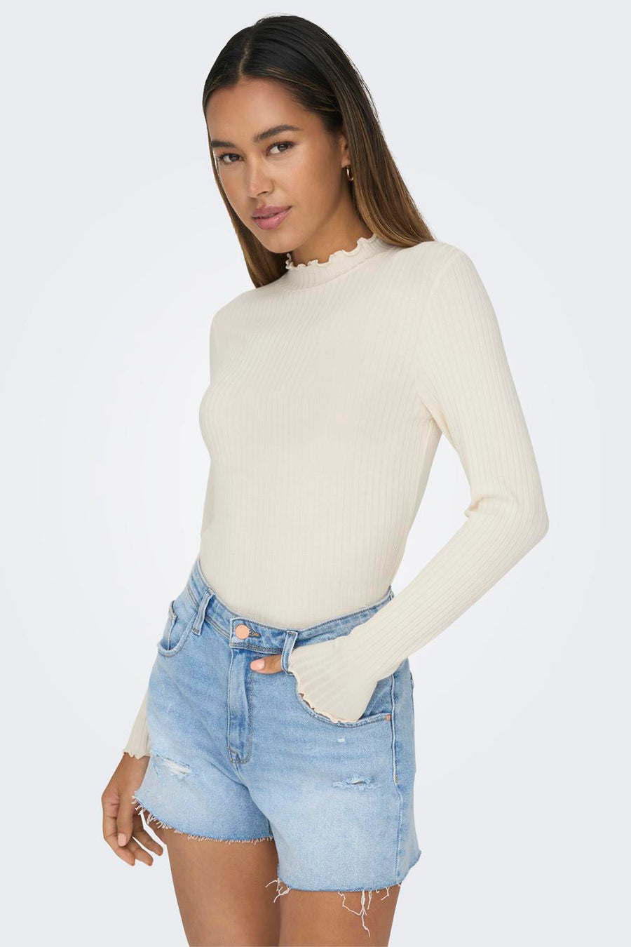 Top beige à manches longues de JDY, avec col montant volanté et texture côtelée, porté avec un short en jean.

