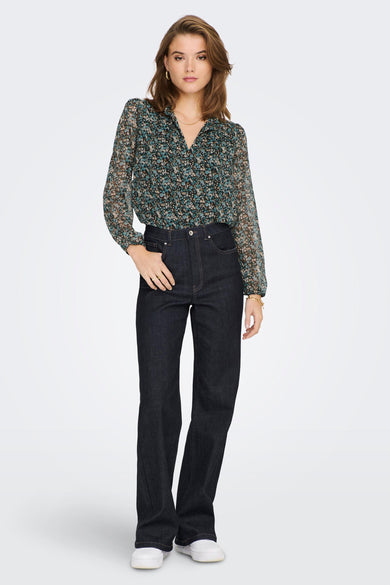 Green floral long-sleeve blouse with V-neck and sheer fabric, worn with dark jeans and white sneakers, front view.