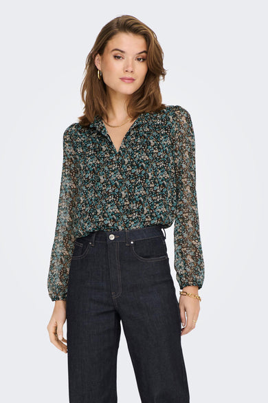 Green floral long-sleeve blouse with V-neck and sheer fabric, worn with dark jeans and gold jewelry, front view.