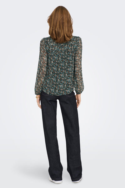 Green floral long-sleeve blouse with sheer fabric and ruffled back, worn with dark jeans, back view