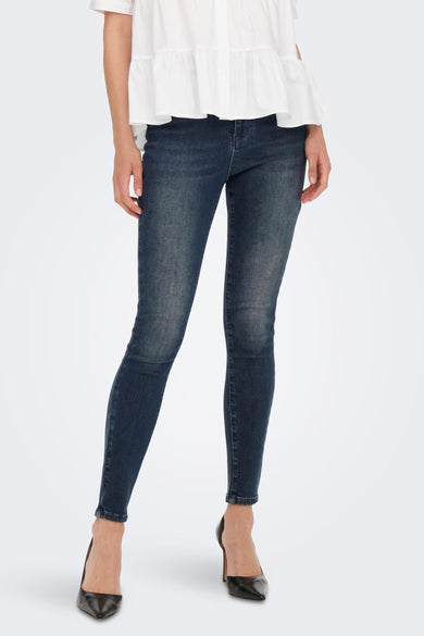 Jean skinny bleu de ONLY, porté avec un chemisier blanc et des escarpins noirs