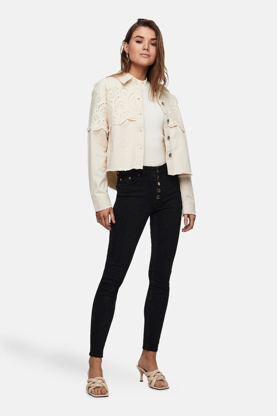 Veste courte écru de ONLY®, avec détails ajourés, portée avec un t-shirt blanc et un jean noir taille haute.