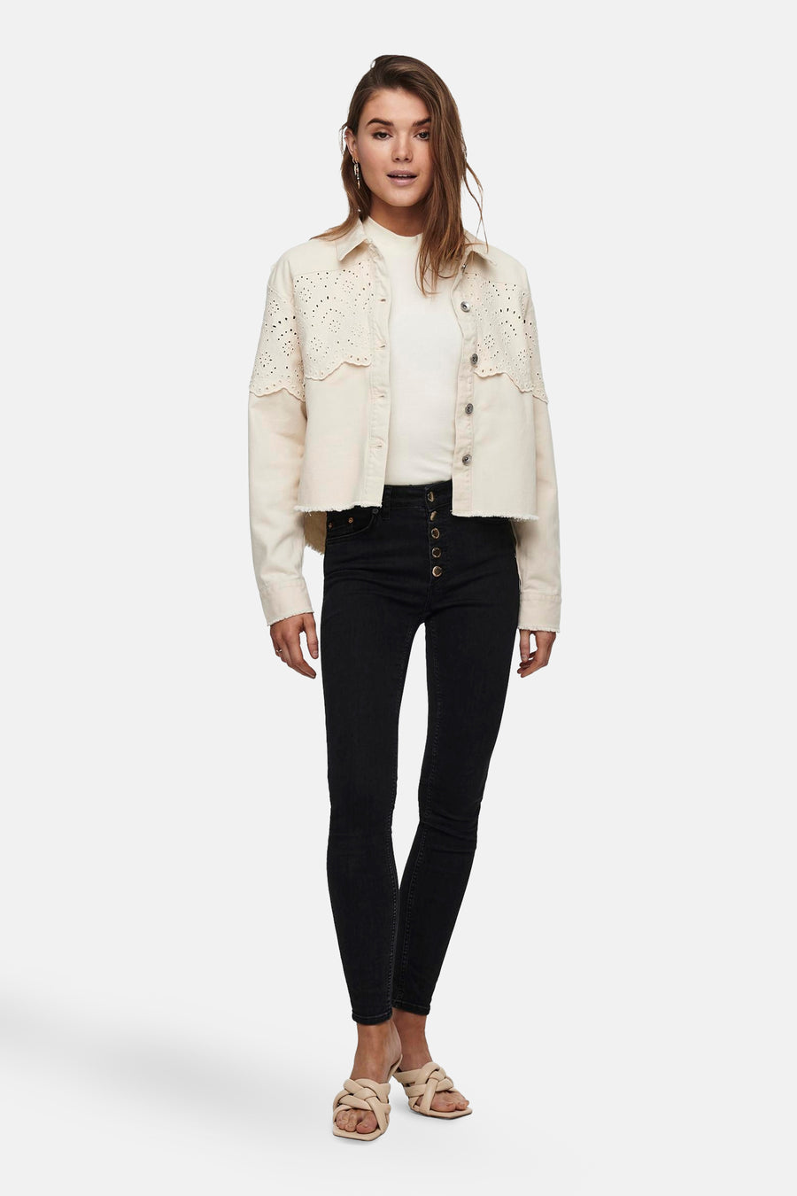 Veste courte écru de ONLY, avec détails ajourés et boutons, portée avec un t-shirt blanc et un jean noir taille haute.