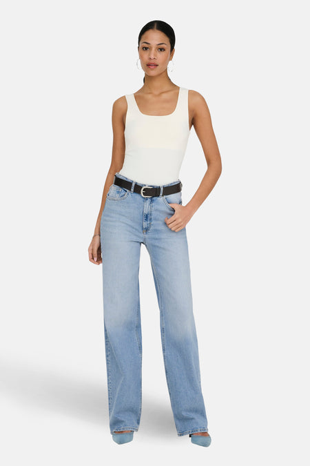 Jean large en denim bleu clair par ONLY, porté avec un débardeur blanc et une ceinture noire.