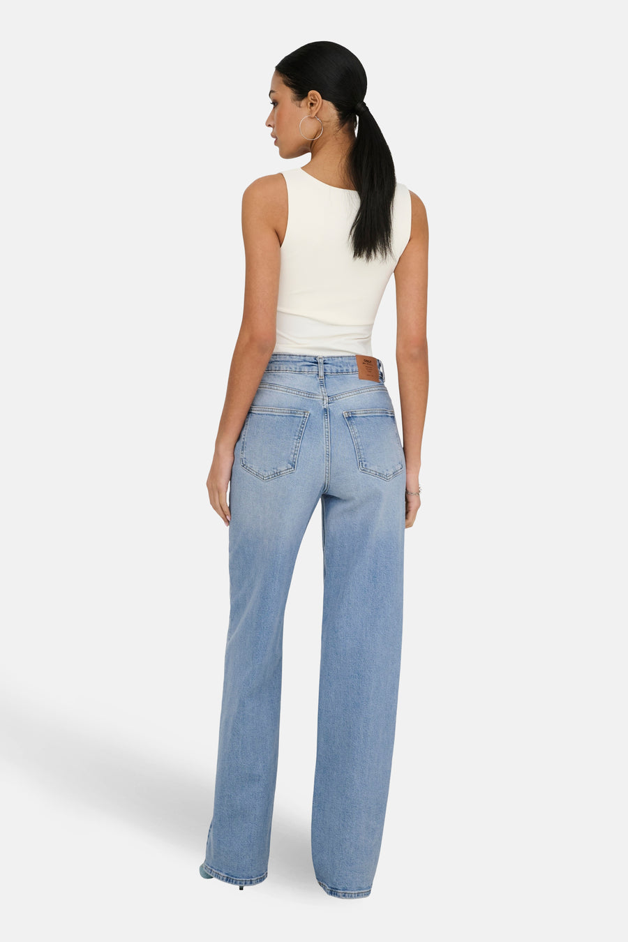 Wijde spijkerbroek in lichtblauw denim van ONLY, met achterzakken, gedragen met een mouwloze witte top.