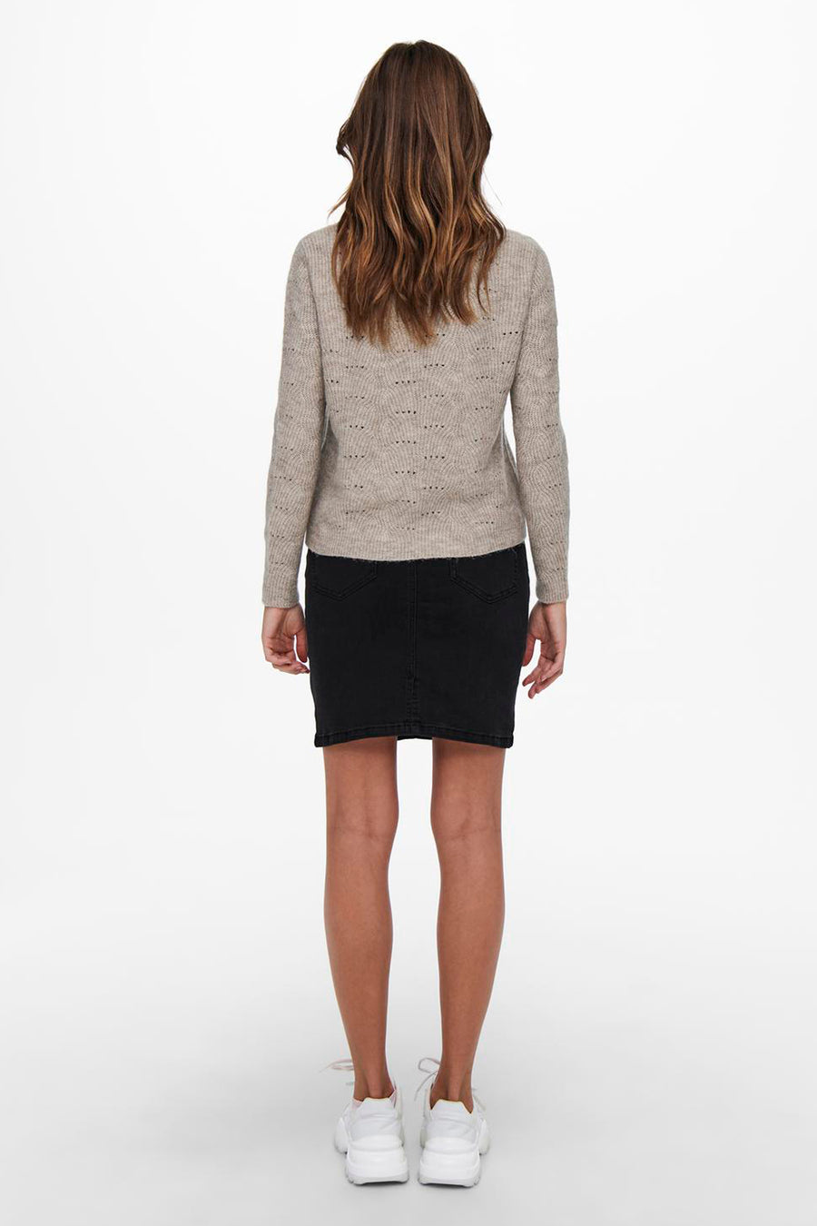 Pull beige col rond de ONLY®, avec motif ajouré et manches longues, porté avec une jupe noire et des baskets blanches.