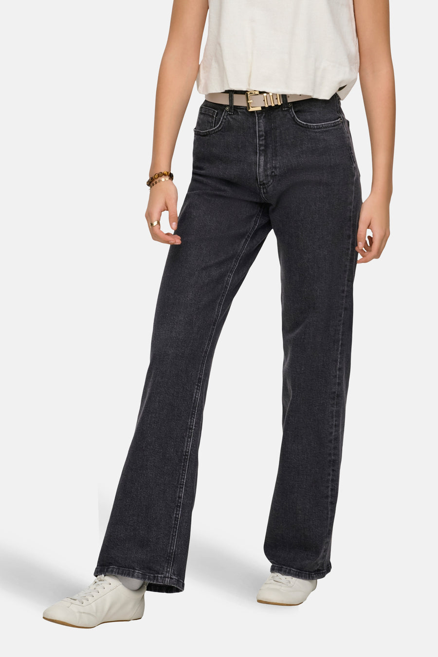 Jean large gris de ONLY, avec une ceinture beige, porté avec un t-shirt blanc et des chaussures de sport blanches.