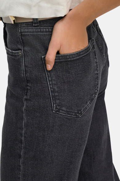 Jean large gris de ONLY, avec une main dans la poche arrière, porté avec une ceinture claire.
