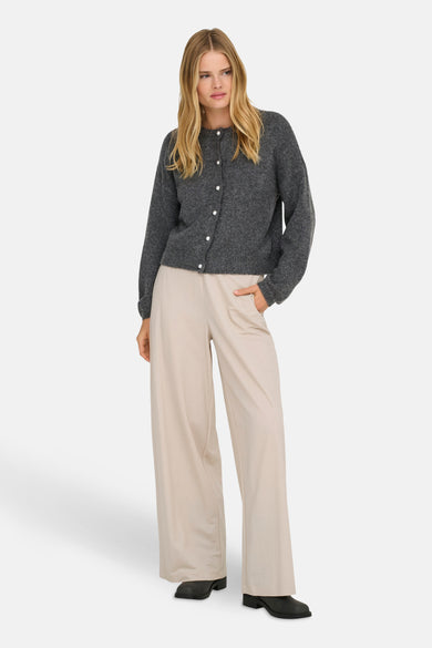 Cardigan gris chiné par ONLY, avec une rangée de boutons nacrés, porté avec un pantalon beige ample.