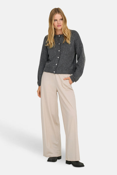 Cardigan gris chiné par ONLY, avec une rangée de boutons nacrés, porté avec un pantalon beige ample.