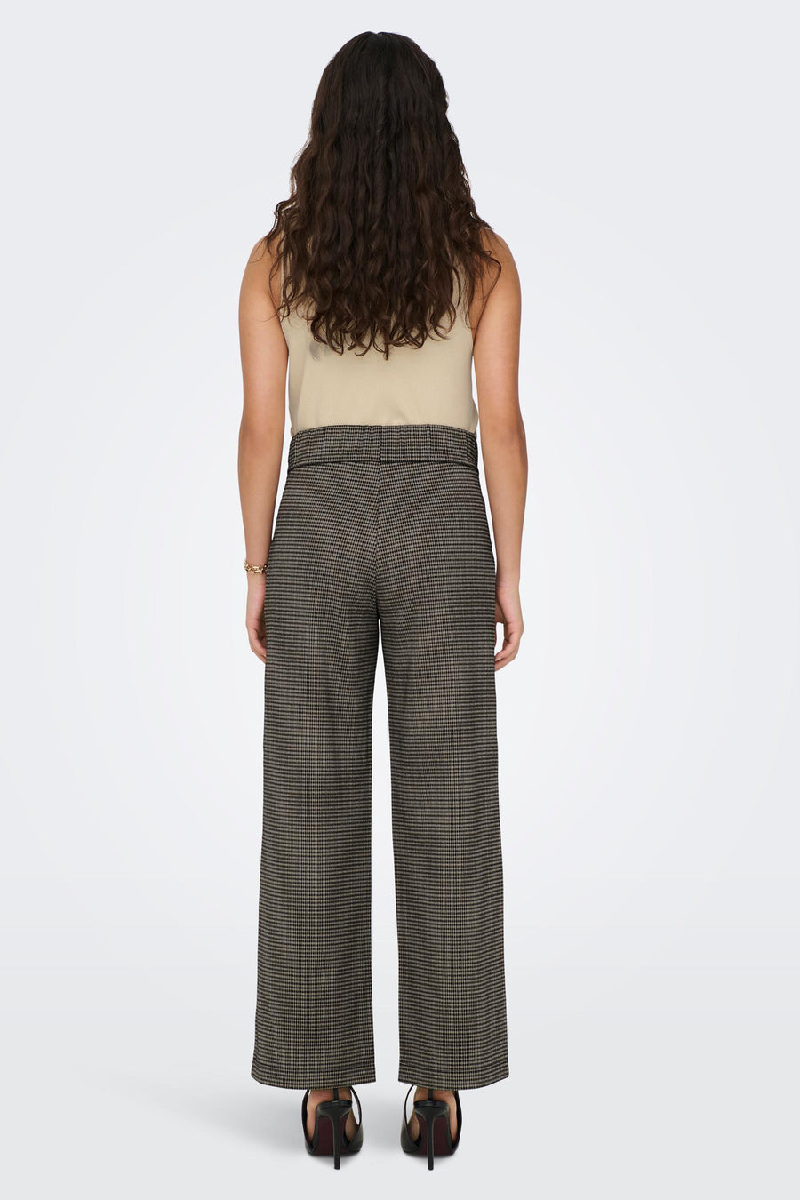 Pantalon gris à carreaux par JDY, coupe large, avec un haut beige et des chaussures noires à talons.
