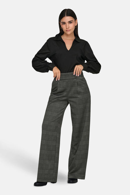 Pantalon gris à carreaux JDY, coupe ample avec poches, porté avec un chemisier noir.

