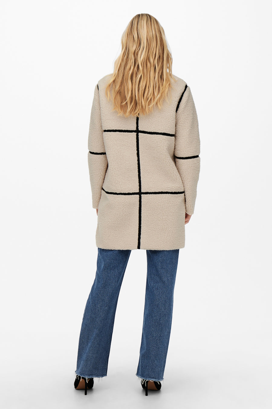 Veste longue écru par JDY, motif à carreaux noirs, portée avec un jean bleu et des chaussures noires.