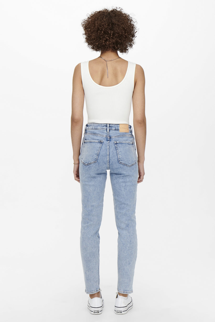 Jean Mom bleu clair de ONLY, porté avec un débardeur blanc et des chaussures Converse blanches.