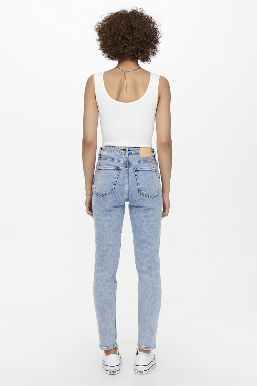 Jean mom blauw van ONLY, gedragen met een witte tanktop en witte sportshoes.