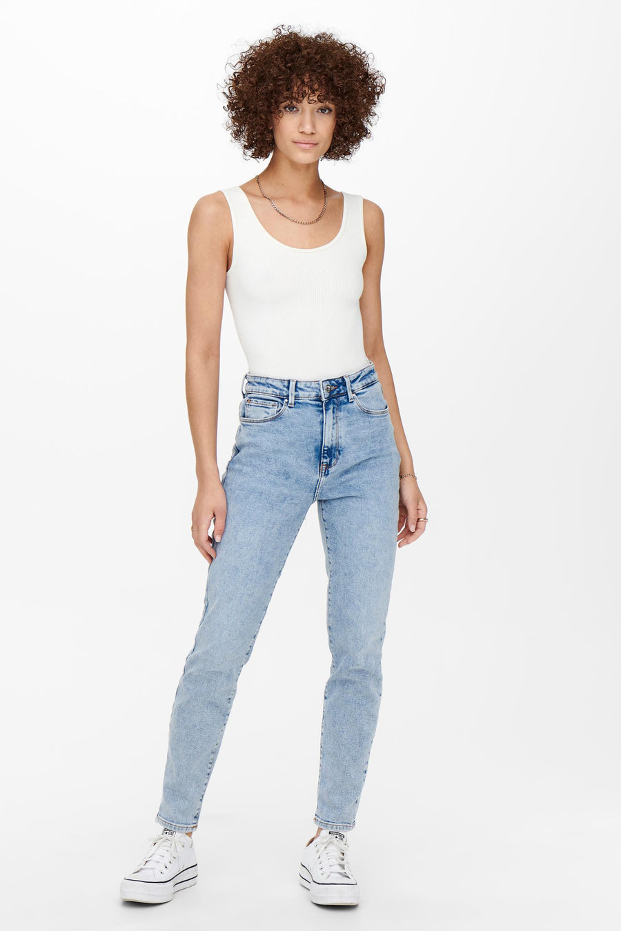 Jean mom en lichte blauwe denim van ONLY, gedragen met een witte tanktop en sneakers.