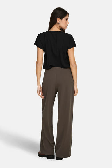 Chemisier noir à manches courtes par JDY, avec une texture légèrement froissée, porté avec un pantalon marron à jambes larges.
