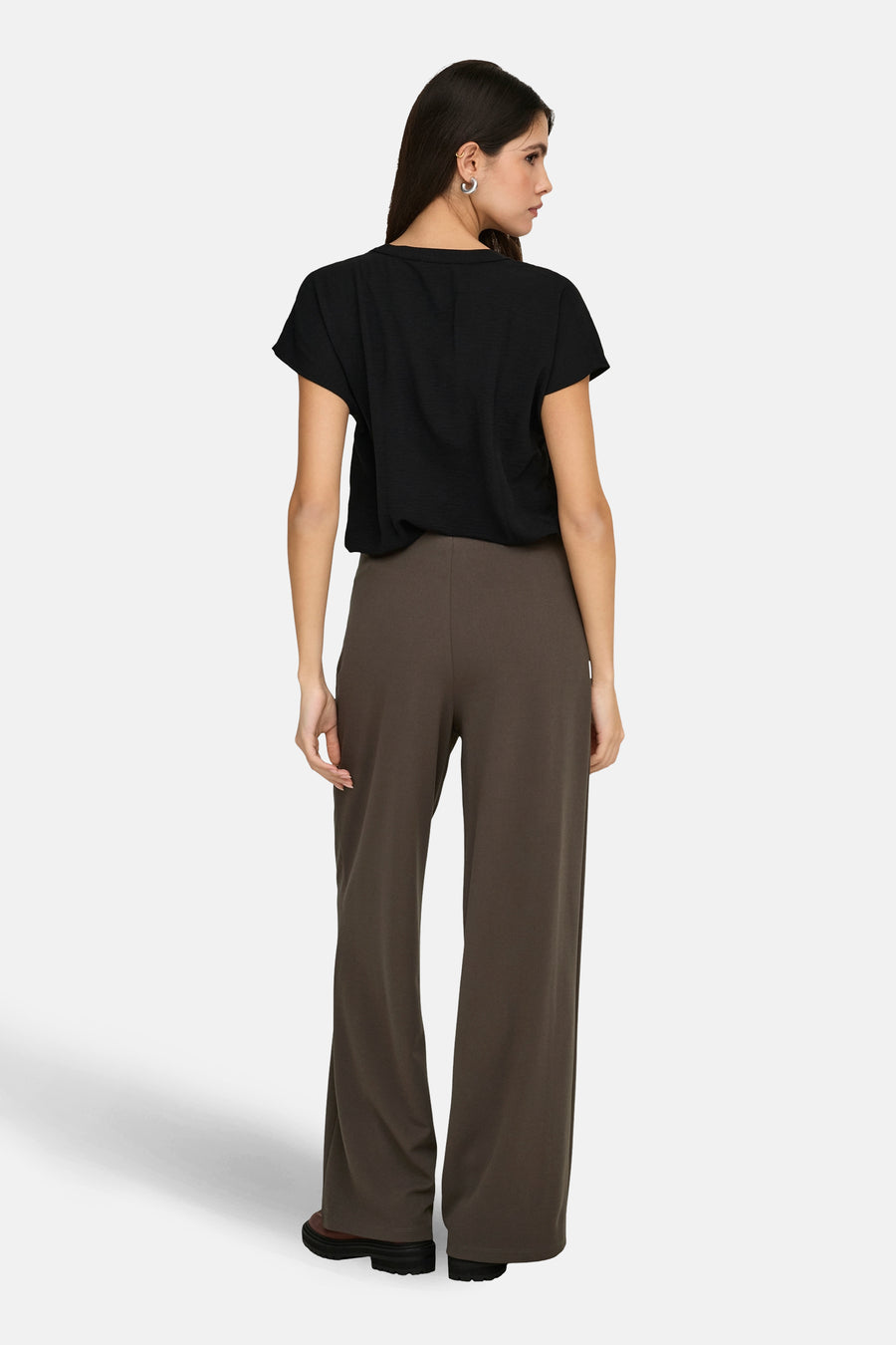 Chemisier noir à manches courtes par JDY, avec une texture légèrement froissée, porté avec un pantalon marron à jambes larges.