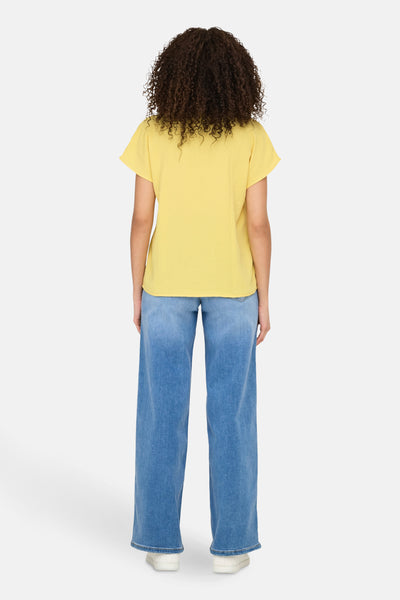 Gele blouse met korte mouwen van JDY, gedragen met een high-waisted spijkerbroek met wijde pijpen.