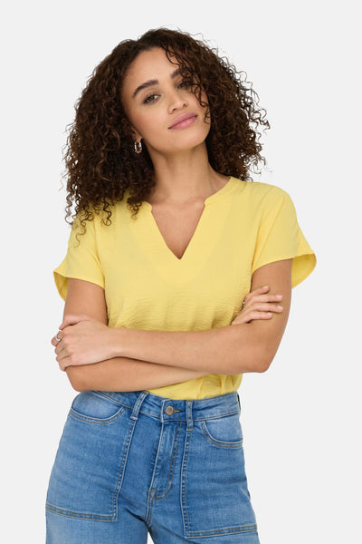 Gele blouse met korte mouwen van JDY, gedragen met een spijkerbroek.