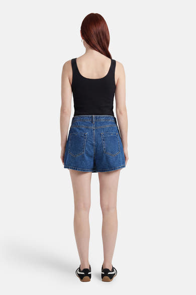 Skort en jean bleu foncé de ONLY® vu de dos, avec poches arrière, porté avec un débardeur noir et des baskets.
