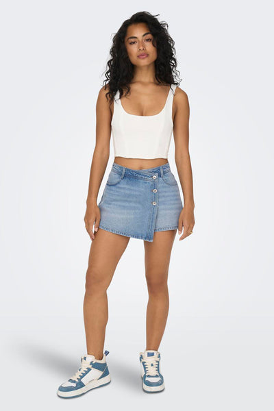 Korte lichtblauwe spijkerrok van ONLY, met asymmetrische knopen, gedragen met een witte tanktop en hoge sneakers.