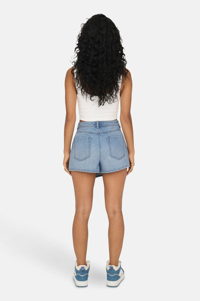 Korte lichtblauwe spijkerbroek van ONLY, gedragen met een witte top en sneakers.