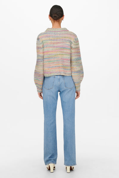 Pull beige en maille chinée de ONLY, porté avec un jean bleu et des chaussures à talons.