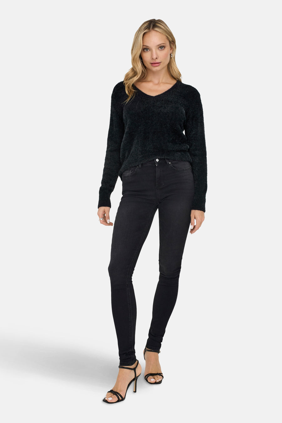 Pull noir à col rond de ONLY, porté avec un jean noir et des talons hauts.
