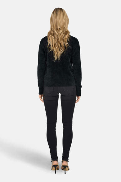 Pull à col rond noir de ONLY, avec une texture duveteuse, porté avec un jean skinny noir et des talons aiguilles.
