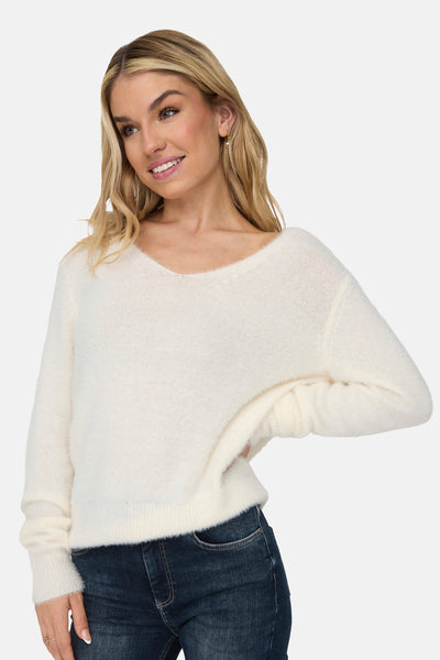 Pull blanc à col rond de ONLY, porté avec un jean bleu foncé.