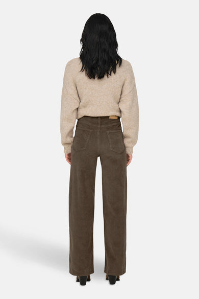 Pantalon coloré brun de ONLY, en velours côtelé à jambes larges, porté avec un pull beige.