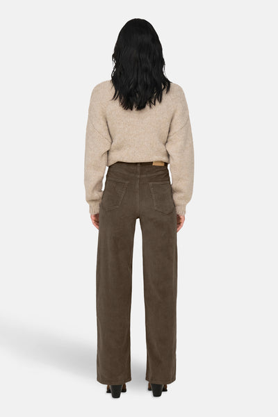 Pantalon coloré brun de ONLY, en velours côtelé à jambes larges, porté avec un pull beige.