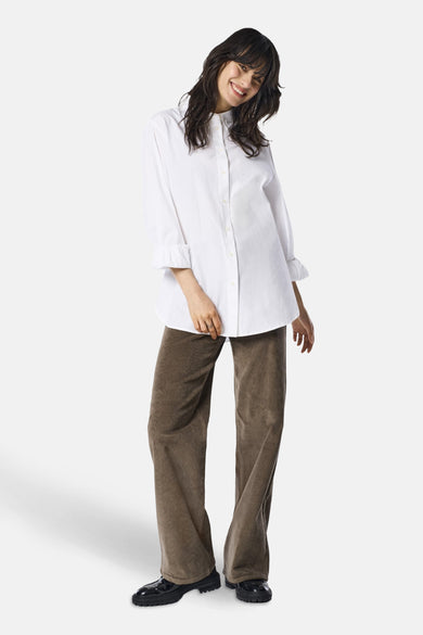 Pantalon coloré brun de ONLY, porté avec une chemise blanche à manches trois-quarts et des chaussures noires brillantes.

