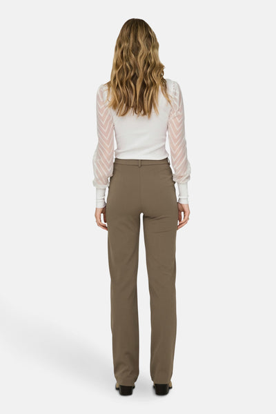 Pantalon brun de ONLY, coupe droite, porté avec un chemisier blanc à manches bouffantes.
