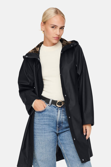 Imperméable noir de ONLY, à capuche avec doublure imprimée léopard, porté avec un jean et une ceinture noire.
