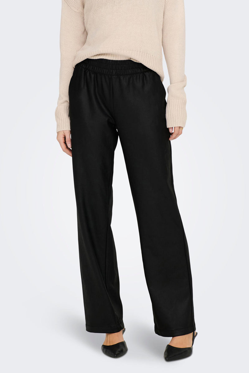 Pantalon noir de ONLY, avec taille élastique, porté avec un pull beige en maille et des escarpins noirs.
