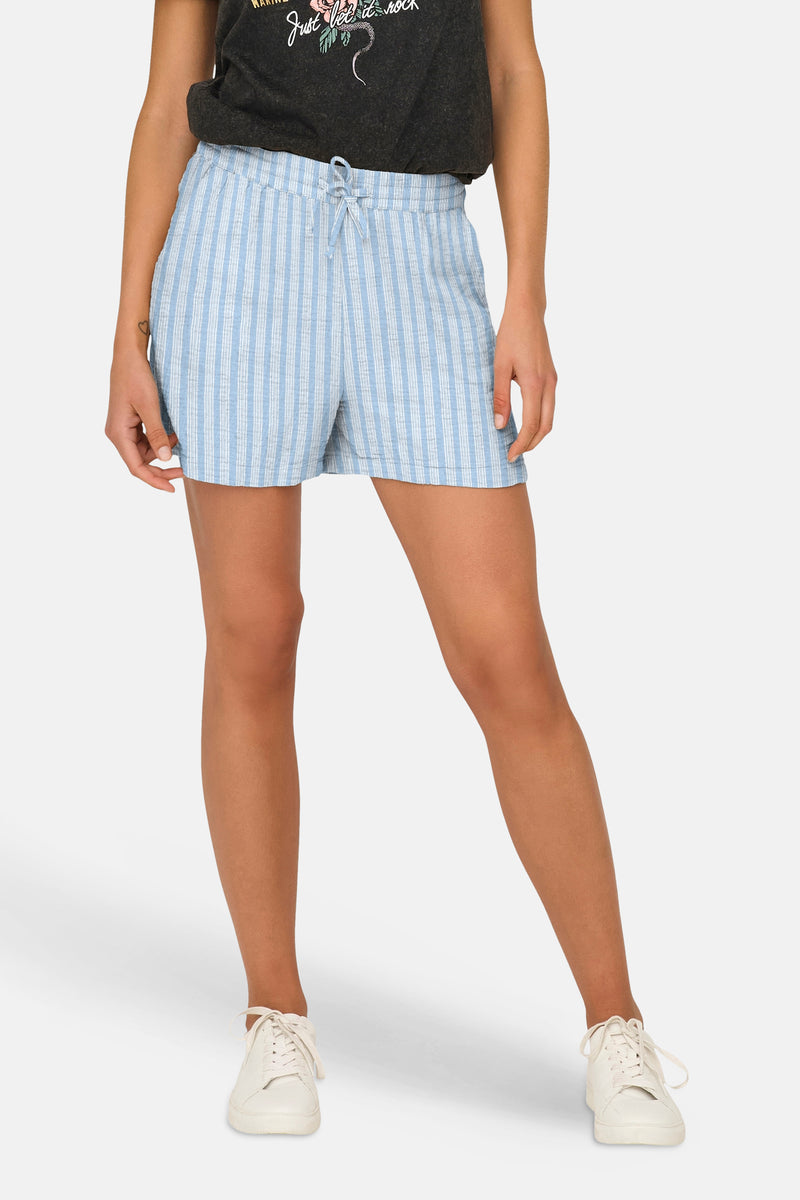 Short rayé bleu et blanc de ONLY® avec taille élastiquée, porté avec un t-shirt foncé et des baskets blanches.