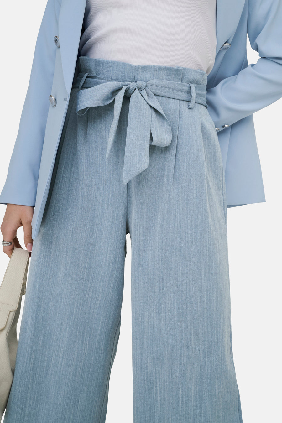 7/8 chino blauw van ONLY®, met een strikceintuur in de taille, gedragen met een lichtblauwe blazer en een witte top.