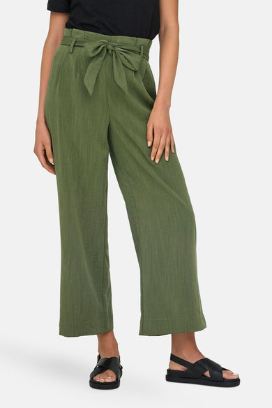 Pantalon chino 7/8 vert de ONLY, avec une ceinture nouée et porté avec des sandales noires.
