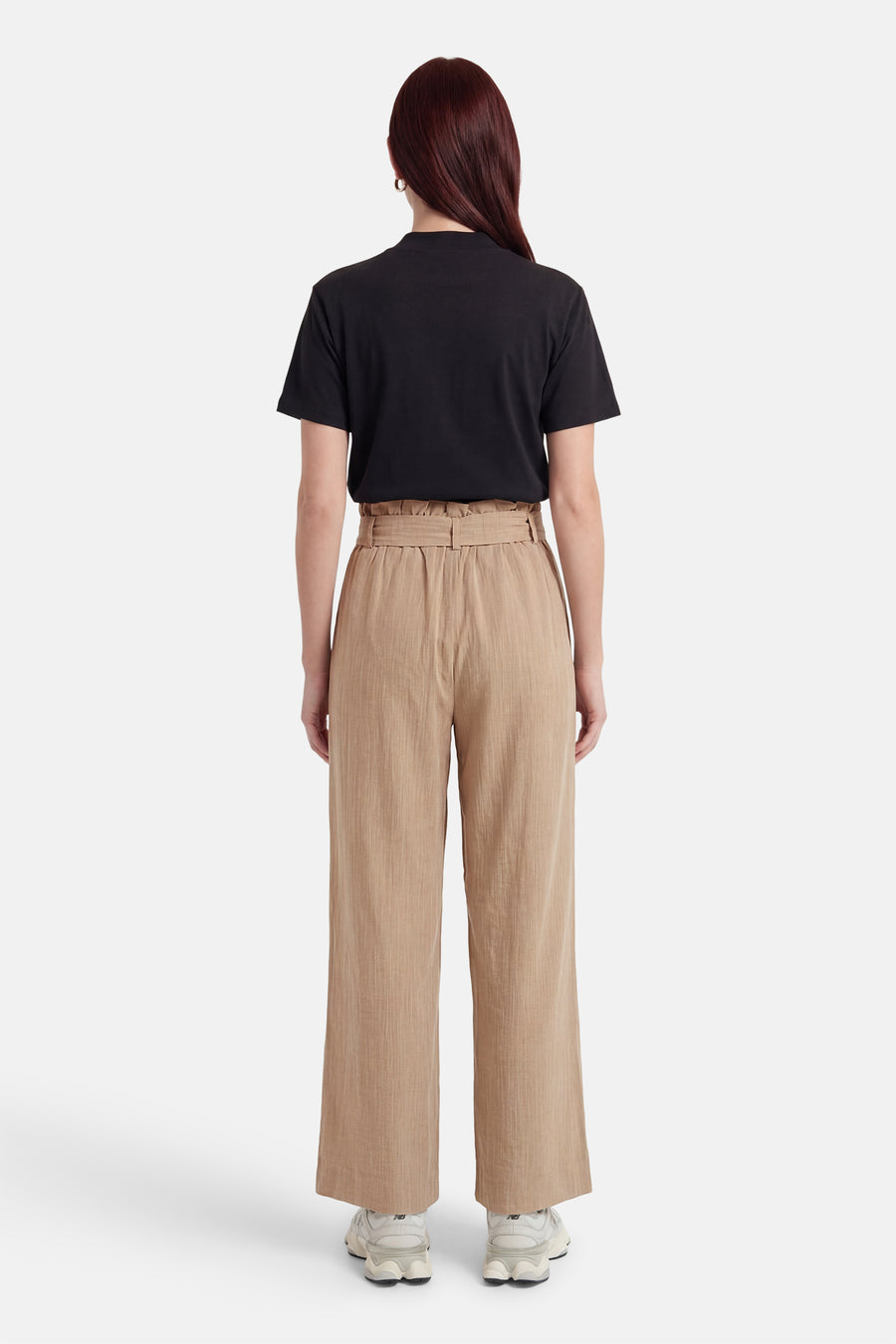 Beige 7/8 chino broek van ONLY met getextureerde paperbag taille, gedragen met een zwart T-shirt en sneakers, van achteren gezien.