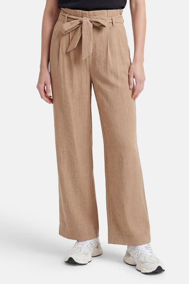 Beige chino broek van ONLY® met paperbag taille, strikceintuur en wijde pijpen, gedragen met een zwarte top en witte sneakers.