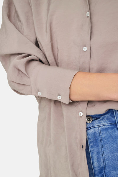 Beige lange mouw chemise van ONLY, met een subtiel texturen en pailletten knoppen, gedragen met een blauwe jeans.