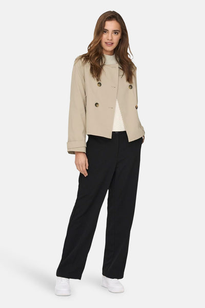 Veste courte beige par ONLY® avec boutonnage croisé, portée sur un pull blanc à col roulé et un pantalon noir.