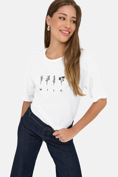T-shirt à manches courtes blanc de JDY, avec imprimé floral et inscription "WILD", porté avec un jean bleu foncé.
