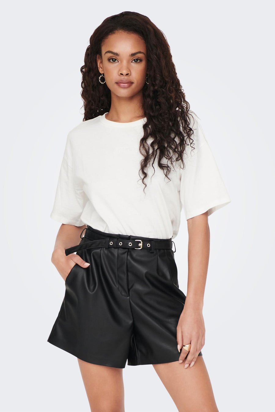 Korte imitatielederen short van ONLY, gedragen met een riem en hoge laarzen.