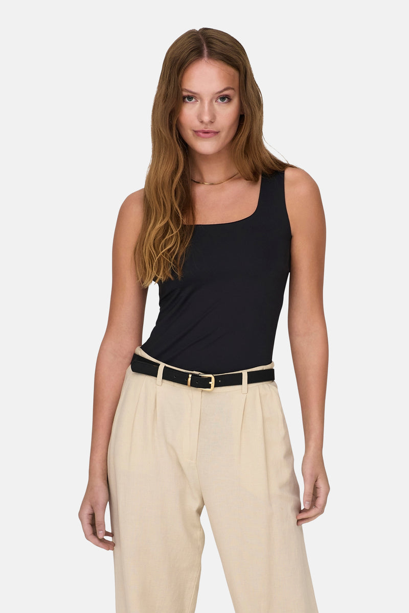 Top noir de ONLY, porté avec un pantalon beige et une ceinture noire à boucle dorée.